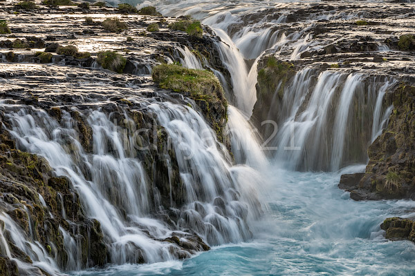 Close-up view of the cascades of Bruarfoss at dusk, soft long-exposure waterfalls over dark rocks in Iceland